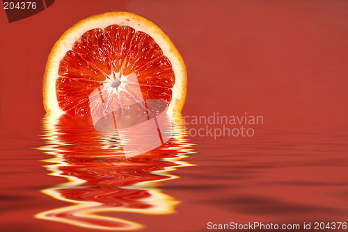 Image of Half of a blood orange in water on a red background