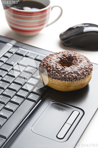 Image of break in the  office . doughnut on laptop keyboard