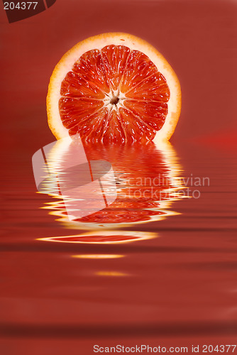 Image of Juicy half of a blood orange in water on a red background