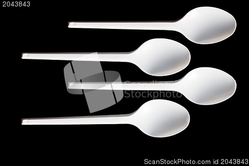 Image of plastic spoons on black background