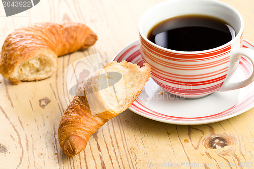 Image of breaking croissant with coffee