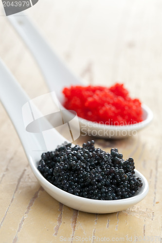 Image of red and black caviar in ceramic spoon