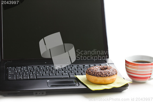 Image of break in the  office . doughnut on laptop keyboard