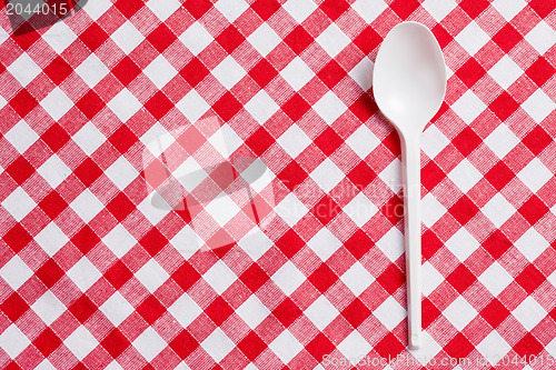 Image of plastic spoon on checkered tablecloth