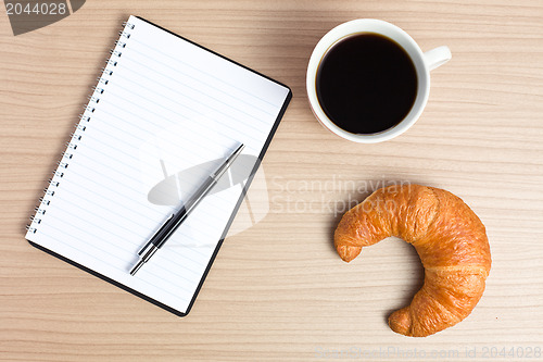 Image of croissant with coffee and notepad