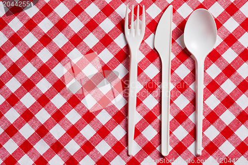 Image of plastic cutlery on checkered tablecloth