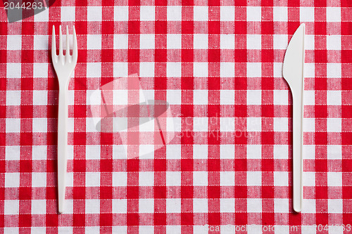 Image of plastic cutlery on checkered tablecloth