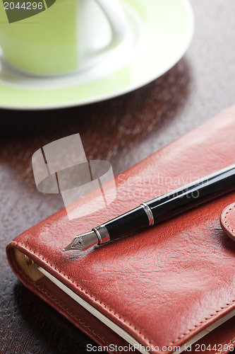 Image of pen on diary and coffee mug