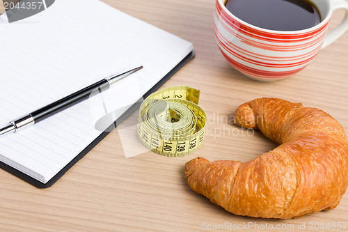 Image of diet concept . croissant and measuring tape