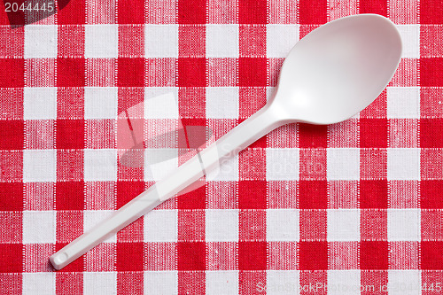 Image of plastic spoon on checkered tablecloth