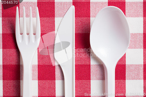 Image of plastic cutlery on checkered tablecloth
