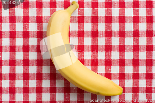 Image of yellow banana on checkered tablecloth