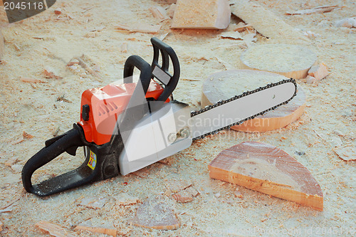 Image of Chainsaw is on background wooden shavings