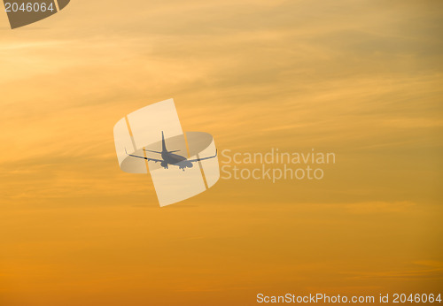 Image of Jetliner flying against red sunset sky