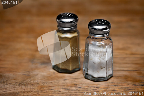 Image of Saltshaker and pepper shaker on a wooden table.