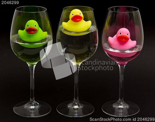 Image of Green, yellow and pink rubber ducks in wineglasses