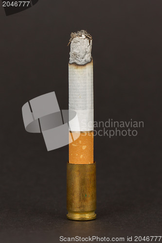 Image of Burning cigarette in an old tin ashtray