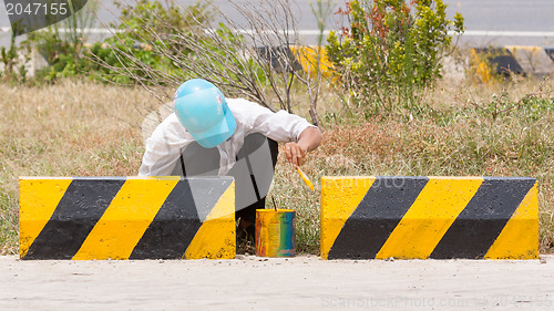 Image of Man painting roadworks barriers on a road in Vietnam