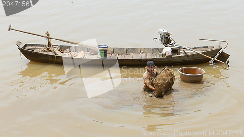 Image of A vietnamese fisherman is searching for shells in the water