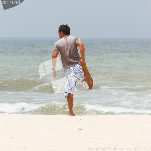 Image of Man stretching on the beach at the south chinese sea 