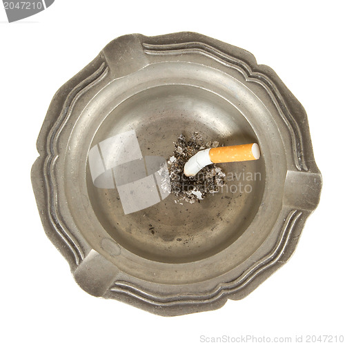 Image of Burning cigarette in an old tin ashtray