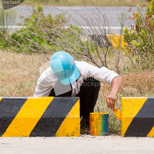 Image of Man painting roadworks barriers on a road in Vietnam