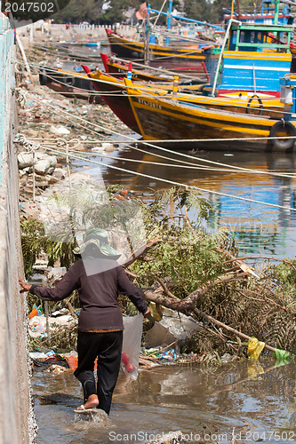 Image of Woman collecting garbage in a harbour in Vietnam
