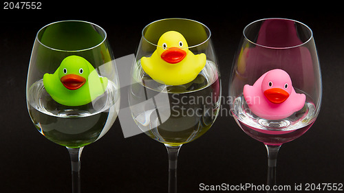 Image of Green, yellow and pink rubber ducks in wineglasses