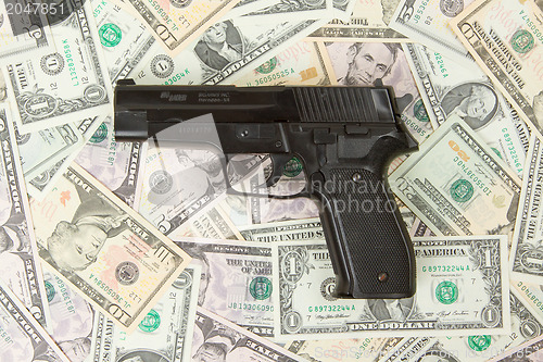 Image of Black gun isolated on a heap of money