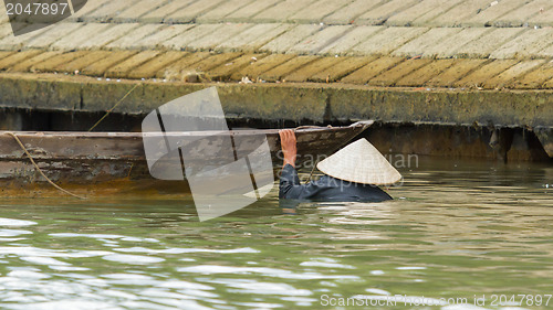 Image of A vietnamese fisherman is searching for shells in the water