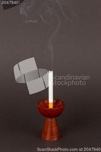 Image of Burning cigarette in a candleholder