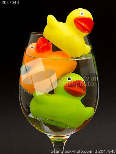 Image of Yellow, orange and green rubber duck in a wineglass