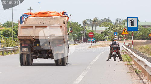 Image of Big truck passing a motorcycle on a highway