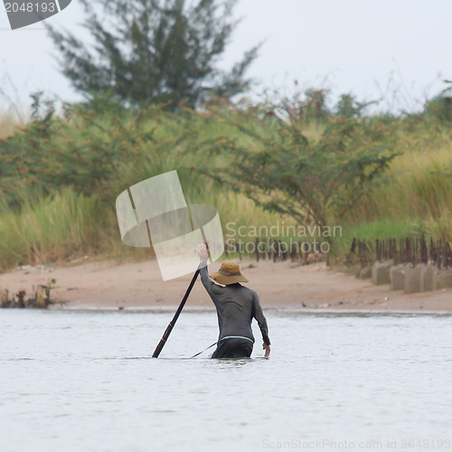 Image of A vietnamese fisherman is searching for snakes and shells in the