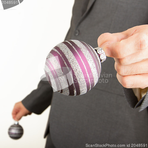 Image of Man in grey suit is holding Christmass balls