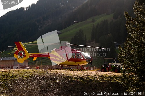 Image of Grounded Yellow and Red Helicopter At Hangar