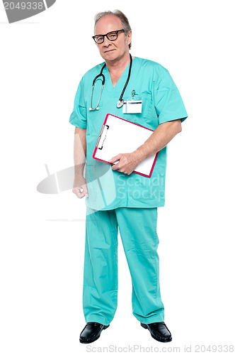 Image of Portrait of grim faced doctor holding a clipboard