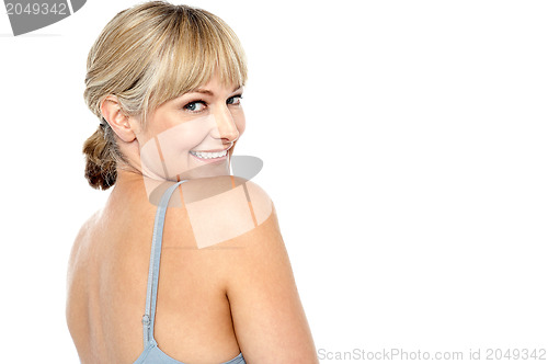 Image of Flirtatious woman turning back and passing a smile