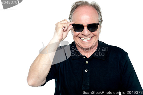 Image of Fashionable cheerful aged man adjusting his shades