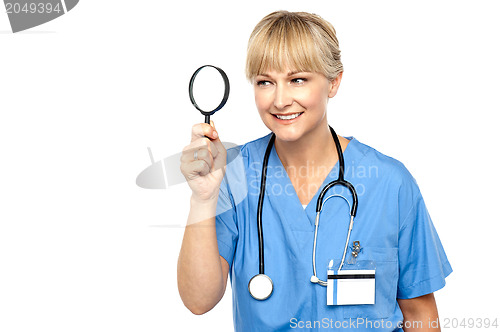 Image of Pretty physician looking through magnifying glass