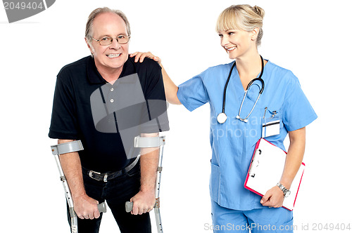 Image of Cheerful doctor encouraging her patient to walk with crutches