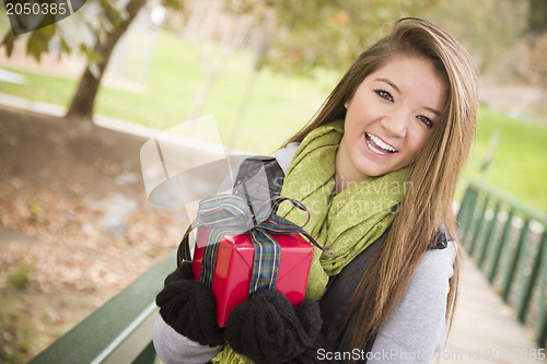 Image of Pretty Woman with Wrapped Gift with Bow Outside