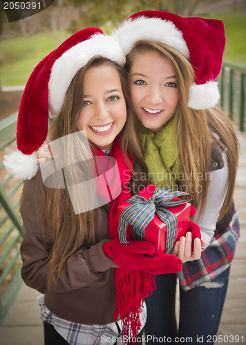 Image of Two Smiling Women Santa Hats Holding a Wrapped Gift