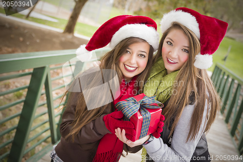 Image of Two Smiling Women Santa Hats Holding a Wrapped Gift