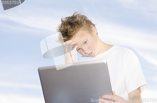Image of Youngster with laptop against blue sky