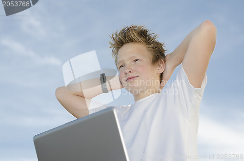 Image of Resting teenager with laptop holding hands behind his head again