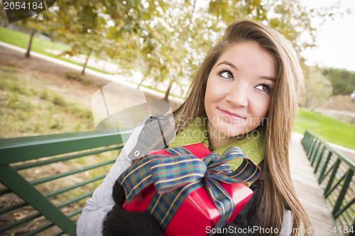 Image of Pretty Woman with Wrapped Gift with Bow Outside