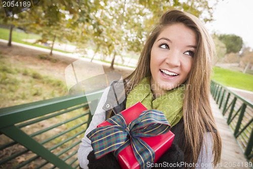 Image of Pretty Woman with Wrapped Gift with Bow Outside