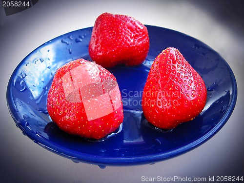 Image of three ripe strawberry on the blue plate