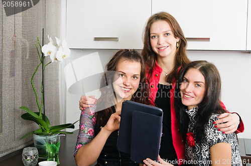 Image of Three young women friends chatting at home and using laptop to l